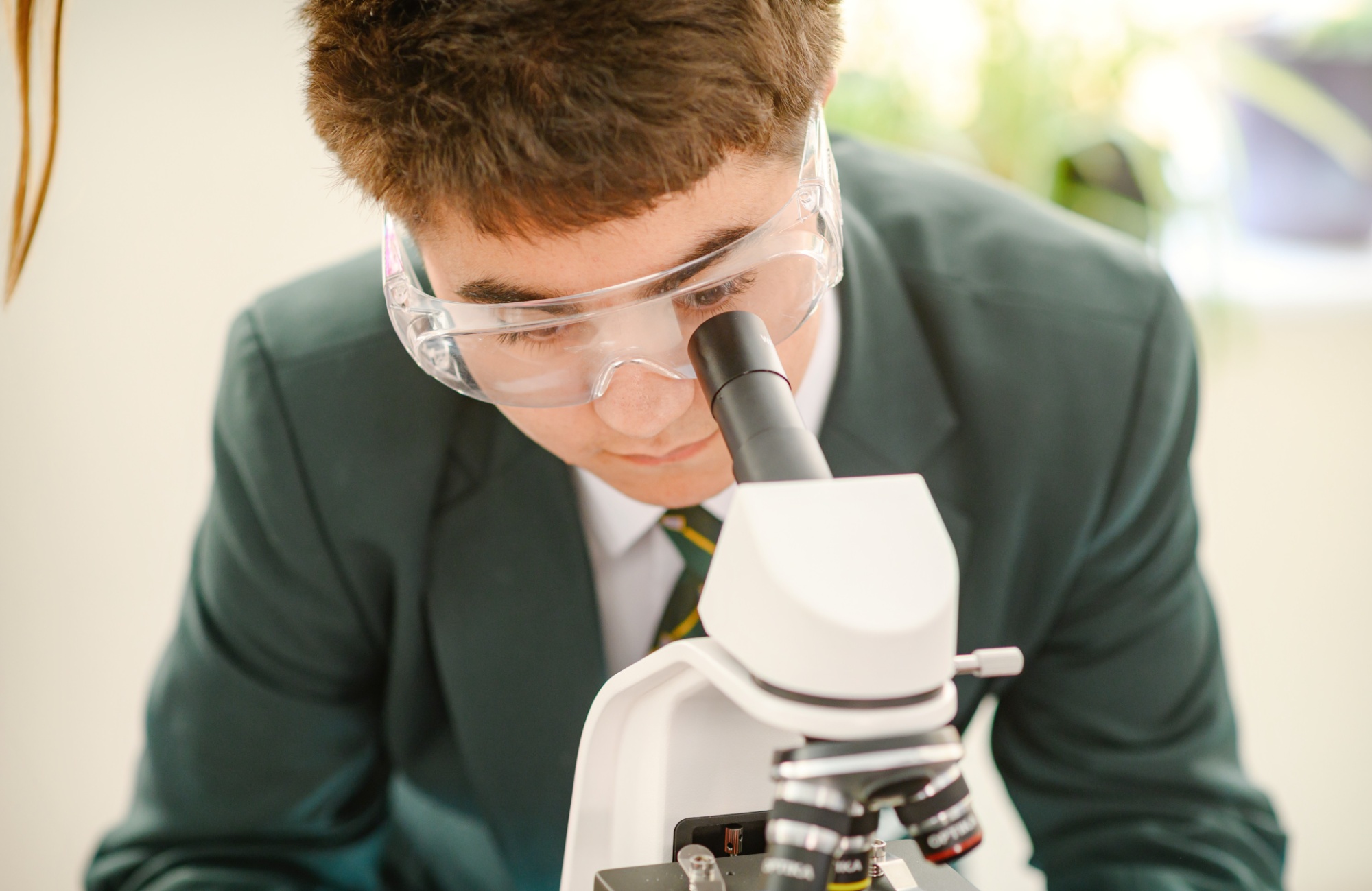 A boy in Argyle House uniform looks into a microscope.