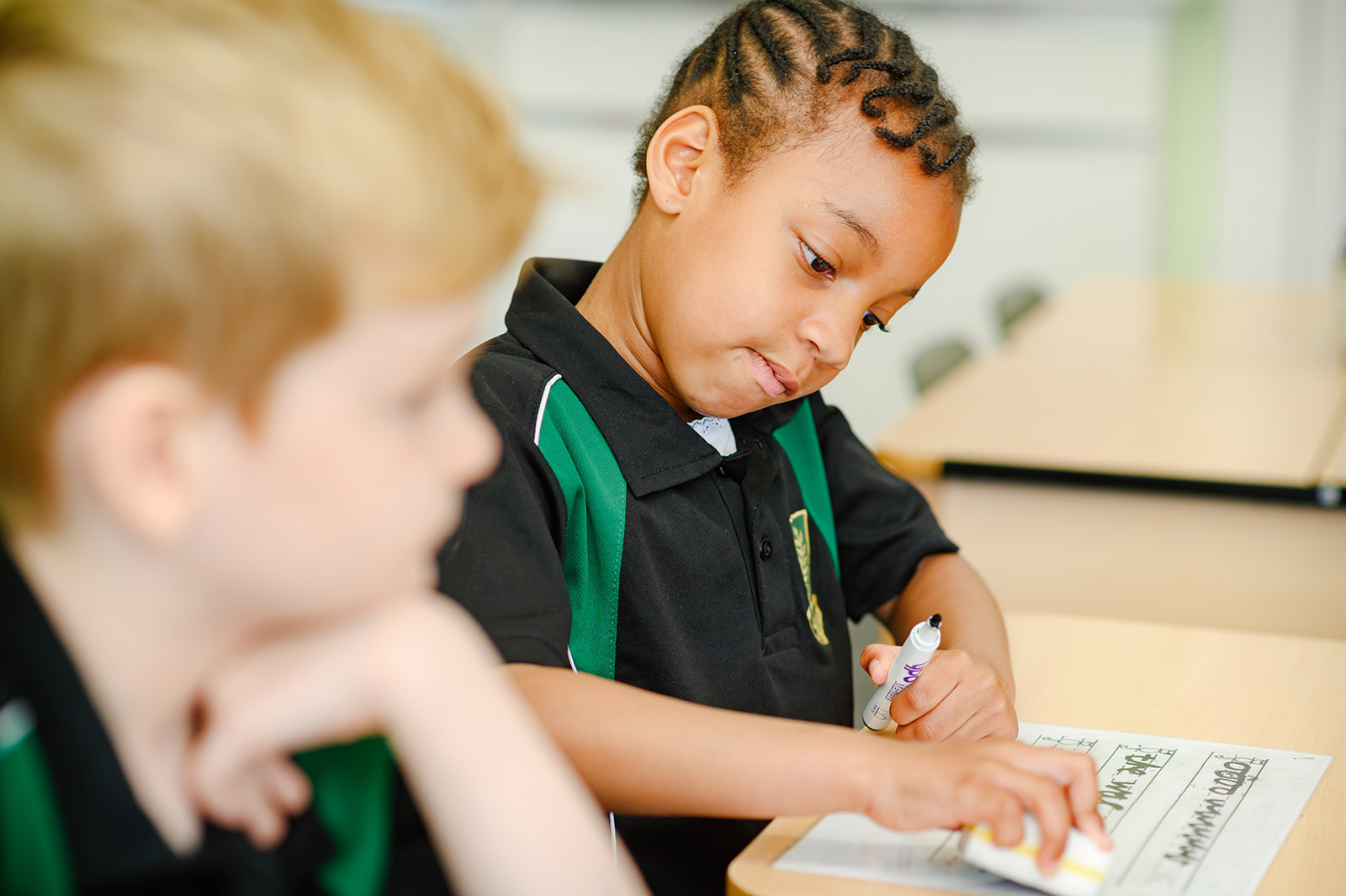Two young students at Argyle House School in a lesson. One is writing on a whiteboard.